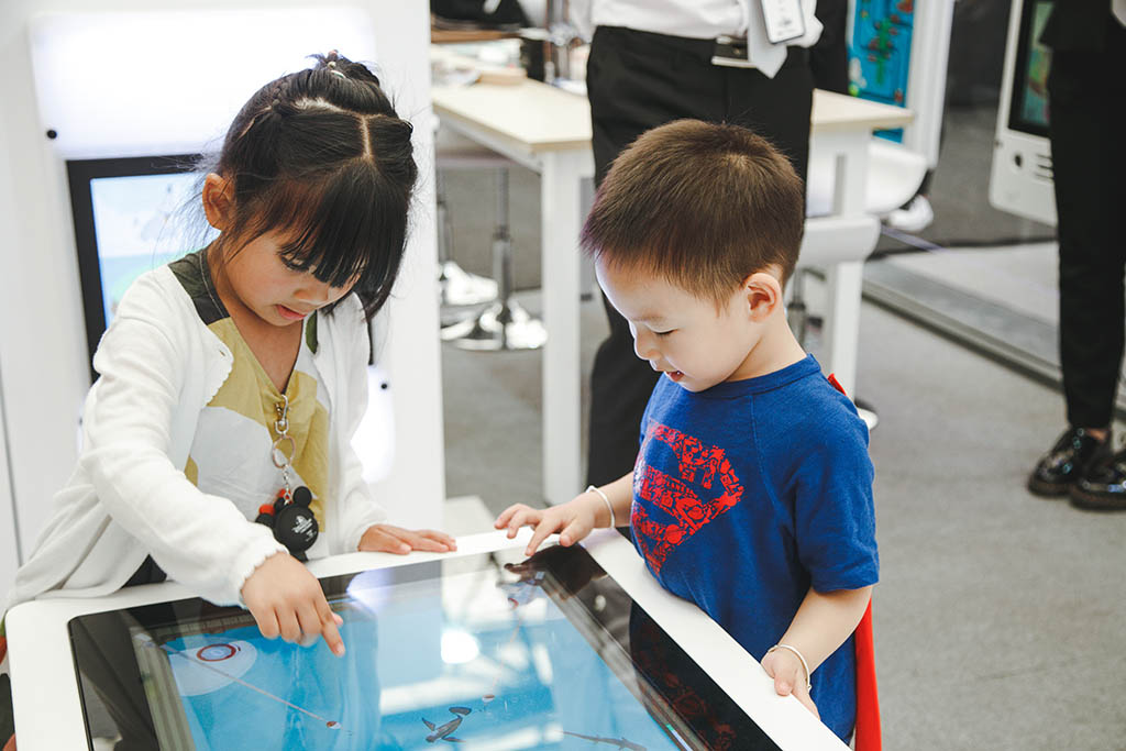 Dos niños ocupados jugando con los sistemas de juegos interactivos de IKC